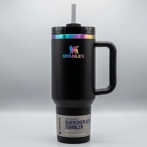 Op de afbeelding: Zwarte Stanley Quencher H2.0 tumbler met een handvat en een rietje. De tumbler heeft een regenboog iriserende rand en logo. Het label luidt "QUENCHER H2.0 TUMBLER" en "40 OZ / 1.18L".