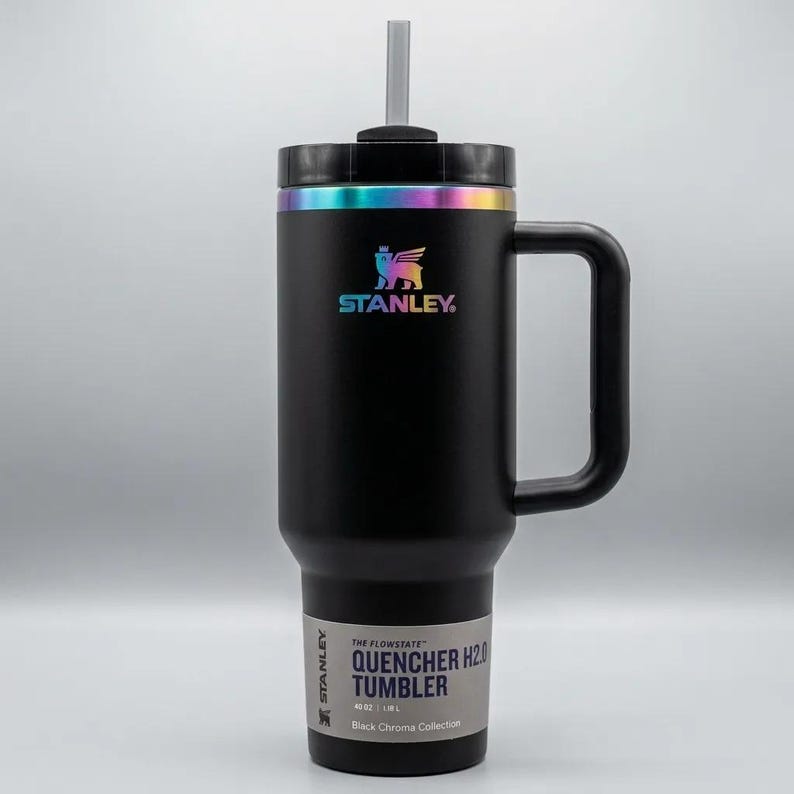 Op de afbeelding: Zwarte Stanley Quencher H2.0 tumbler met een handvat en een rietje. De tumbler heeft een regenboog iriserende rand en logo. Het label luidt "QUENCHER H2.0 TUMBLER" en "40 OZ / 1.18L".
