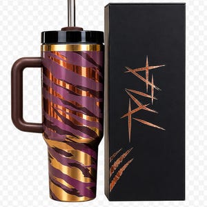 May include: A stainless steel tumbler with a handle, straw, and lid. The tumbler has a purple and gold tiger stripe pattern. A black box with copper-colored text and claw marks is next to the tumbler.