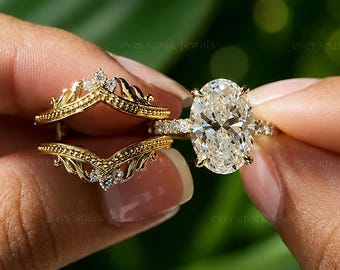 May include: A gold ring set featuring a central oval-cut diamond solitaire ring and a matching chevron-shaped ring guard. The solitaire ring has a prong setting, while the guard displays intricate filigree metalwork and small accent diamonds.