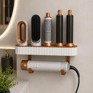 May include: A white and copper wall-mounted storage rack holding a hair dryer and five styling attachments. The rack features a fluted design, with the hair dryer resting in a lower cradle and the various brush and nozzle heads standing upright.