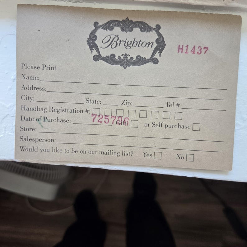 Op de afbeelding: Een vintage Brighton handtassenregistratiekaart. De kaart is beige met gedrukte lijnen voor klantinformatie. Het Brighton-logo staat bovenaan, met de aankoopdatum geschreven als 725786.