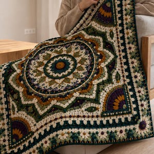 May include: A square crochet blanket featuring a large central mandala pattern in shades of dark green, mustard yellow, cream, and deep purple. The border is decorated with small white daisy-like flowers and intricate textured stitching throughout.