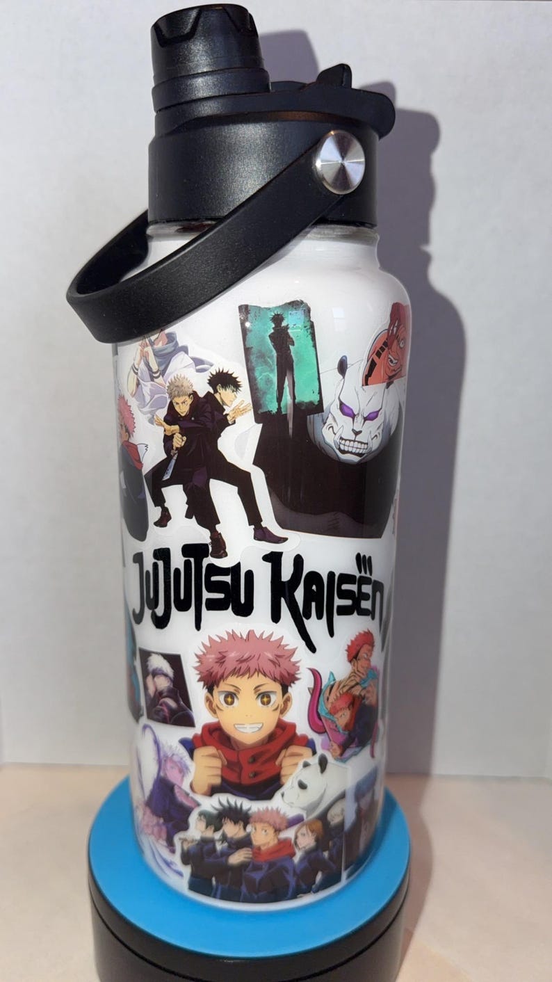 May include: White water bottle featuring colorful anime character graphics and the text "Jujutsu Kaisen." The bottle has a black handle and lid. The bottle is sitting on a blue surface.