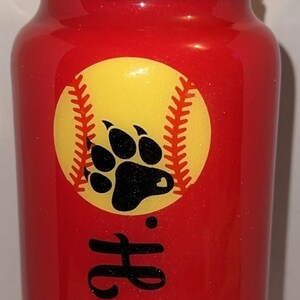 May include: Red water bottle with a black lid and handle. A yellow softball graphic with a black paw print is on the front. The name "Avery H." is written in black script.