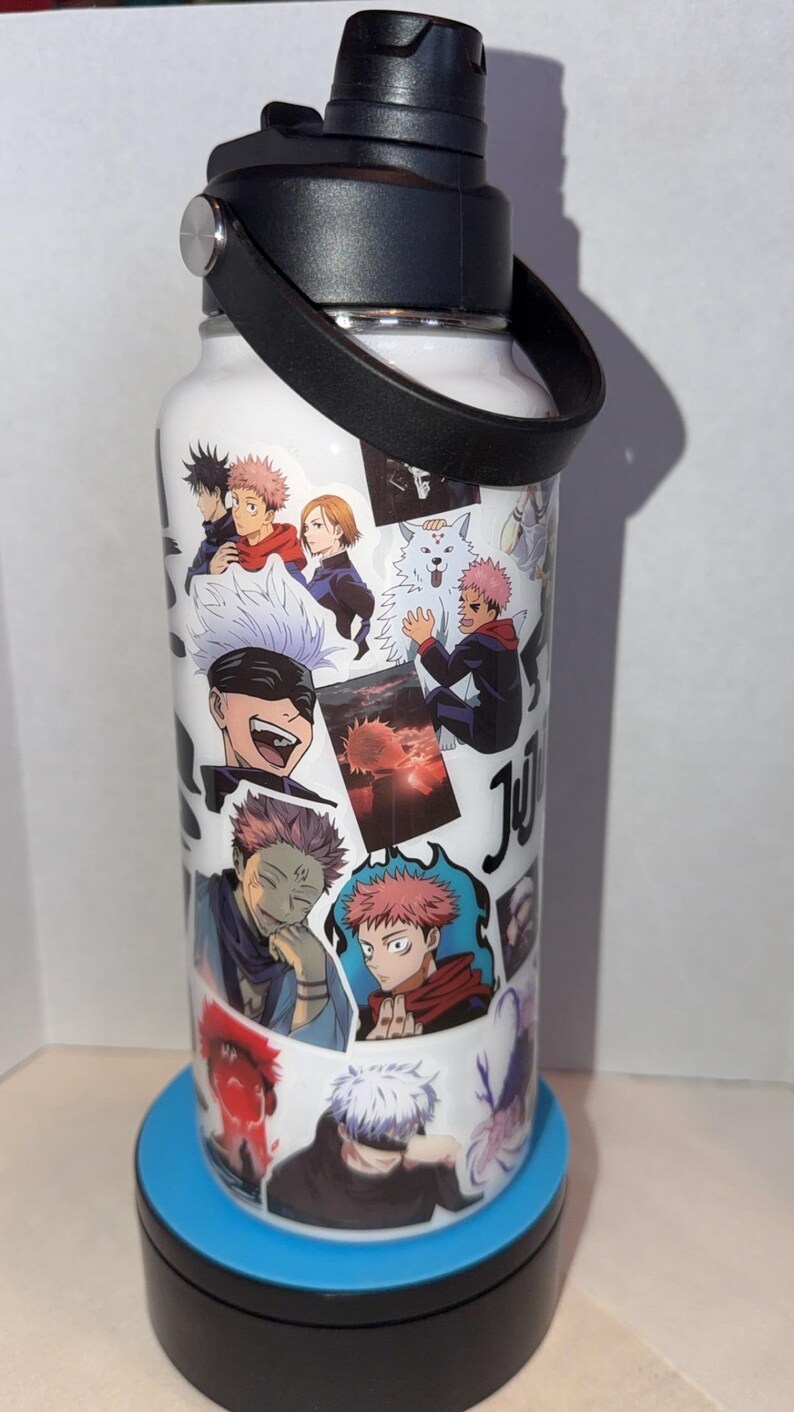 May include: White water bottle featuring anime character illustrations. The bottle has a black lid, a black handle, and a silver accent. The bottle is decorated with various anime character images in different poses and colors.