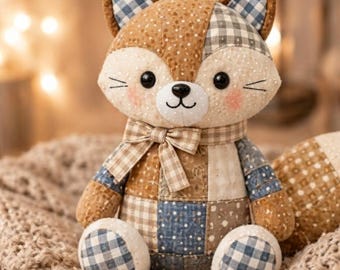 May include: A stuffed fox toy crafted from various fabric patches in shades of brown, cream, and blue. The fox features a gingham bow tie, embroidered whiskers, black button eyes, and a small black nose, with patterned ears and paws.