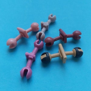 May include: Five plastic toy tools in various colors, including pink, brown, and gray. The tools have different shapes and sizes, and some have a handle.