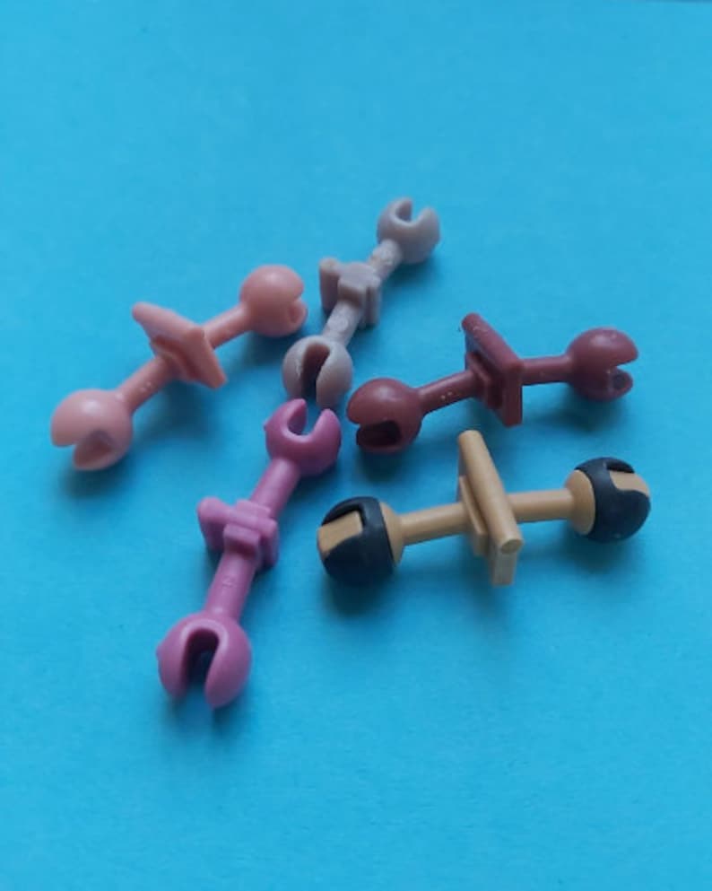 May include: Five plastic toy tools in various colors, including pink, brown, and gray. The tools have different shapes and sizes, and some have a handle.