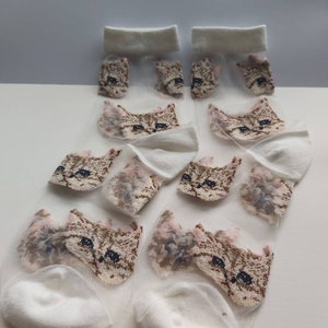 May include: A pair of white sheer socks with a cat face design. The socks are made of a lightweight, breathable material and are perfect for warm weather.