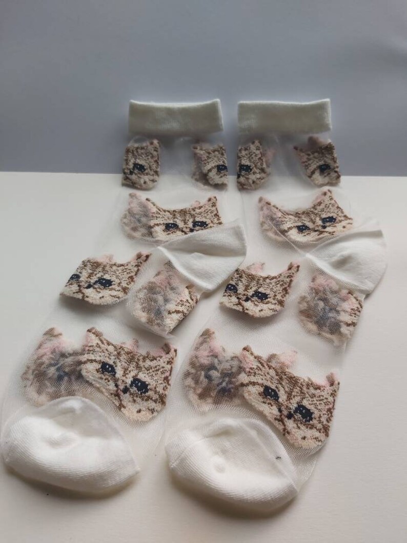 May include: A pair of white sheer socks with a cat face design. The socks are made of a lightweight, breathable material and are perfect for warm weather.