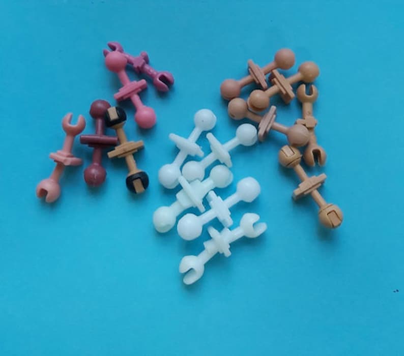 May include: Assortment of plastic toy connectors in white, pink, and brown. The connectors have a ball on one end and a hook on the other end.