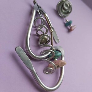 May include: Silver earrings with a spiral design and colorful stones. The earrings are made of metal and have a unique, handmade look.