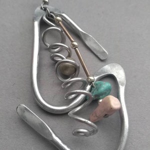 May include: Silver earrings with a unique design featuring a twisted wire, beads, and turquoise and pink stones.
