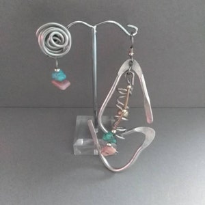 May include: A pair of silver earrings with turquoise and pink stones. The earrings are hanging from a silver stand.