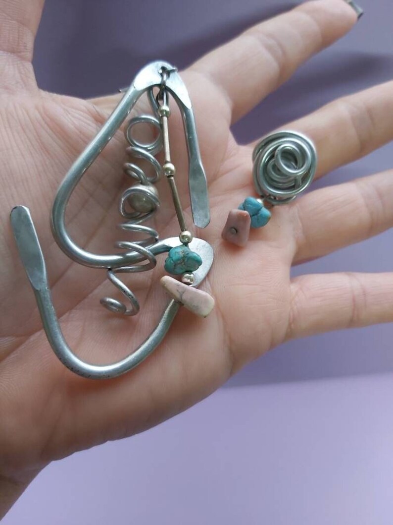 May include: A silver metal earring with a spiral design and turquoise and pink stones.