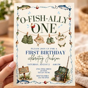 以下が含まれることがあります： O-FISH-ALLY ONEという文字が書かれたクリーム色の1歳の誕生日招待状。釣り用ベスト、帽子、ブーツ、ベビー服が吊るされた水彩画風のイラストと、釣り道具箱、釣り竿、魚のモチーフが描かれています。