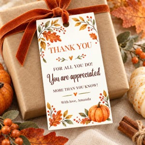 Op de afbeelding: Een rechthoekig wit cadeaulabel met aquarelillustraties van herfstbladeren, bessen en een pompoen. De tekst luidt: THANK YOU FOR ALL YOU DO! You are appreciated MORE THAN YOU KNOW! With love, Amanda. Het label is voorzien van een bruin fluwelen lint.