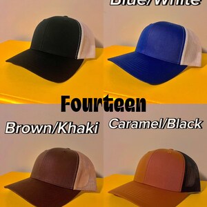 May include: Four baseball caps with mesh backs. Top left is black and white, top right is blue and white, bottom left is brown and khaki, and bottom right is caramel and black. Each cap features a solid front panel and a curved brim.