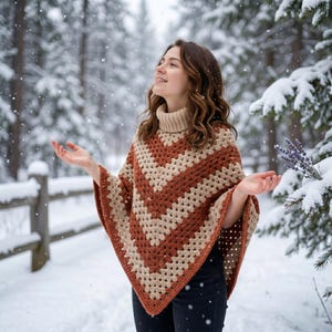 Puede incluir: Un poncho de crochet hecho a mano con un patrón de chevron, en tonos marrones y beige. El poncho tiene un cuello alto y se usa al aire libre en un ambiente nevado. La prenda es un accesorio cálido y acogedor.