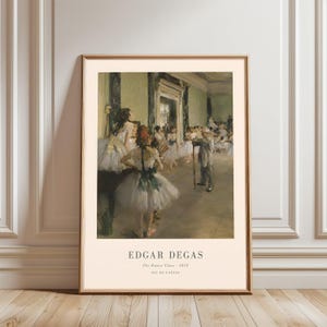 May include: Framed print of Edgar Degas' "The Dance Class - 1874" oil painting. The artwork depicts a ballet class with ballerinas in white tutus and a man in a suit. The print is in a wooden frame and is displayed against a white wall.