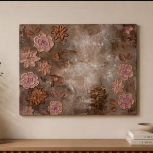 Könnte beinhalten: Abstrakte Blumenmalerei mit strukturierten Details in Braun-, Rosa- und Goldtönen. Das Kunstwerk zeigt stilisierte Blumen und Blätter, die an einer Wand über einer Holzoberfläche angebracht sind. Eine Vase mit Grün und eine brennende Kerze befinden sich auf der Holzoberfläche.