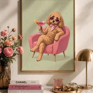 Könnte beinhalten: Ein gerahmter Wandkunstdruck, der einen goldbraunen Pudel mit rosa Sonnenbrille und rosa Halstuch zeigt, der in einem rosa Sessel sitzt und einen rosa Cocktail mit einer Zitronenscheibe vor einem hellgrünen Hintergrund hält.
