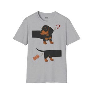 Può includere: Una t-shirt grigia mélange a maniche corte con la grafica di un bassotto nero e focato diviso in due parti. La sezione anteriore mostra il cane con un punto interrogativo rosso, quella posteriore un timbro rosso con la scritta OBVIOUSLY REJECTED.