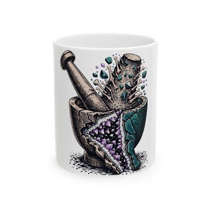 May include: A white ceramic mug featuring a graphic illustration of a mortar and pestle. The mortar is cracked open to reveal purple crystals inside, while the pestle is surrounded by floating small bones and teal-colored gemstone fragments.
