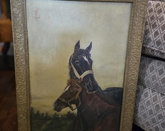 May include: An antique framed painting of two horses. The horses are dark brown and black, with white markings and are wearing bridles. The painting has a gold-colored ornate frame and depicts a landscape background.
