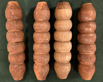 May include: Four wooden, hand-carved spindles. Two are a reddish-brown color, and two are a lighter, natural wood tone. Each spindle is composed of stacked, rounded sections, with a vase-like base and a rounded top. The spindles are arranged vertically.