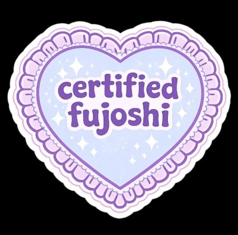 May include: A heart-shaped sticker with a light blue center and a lavender border. The text "certified fujoshi" is written in purple. The sticker has a scalloped edge and small star accents.