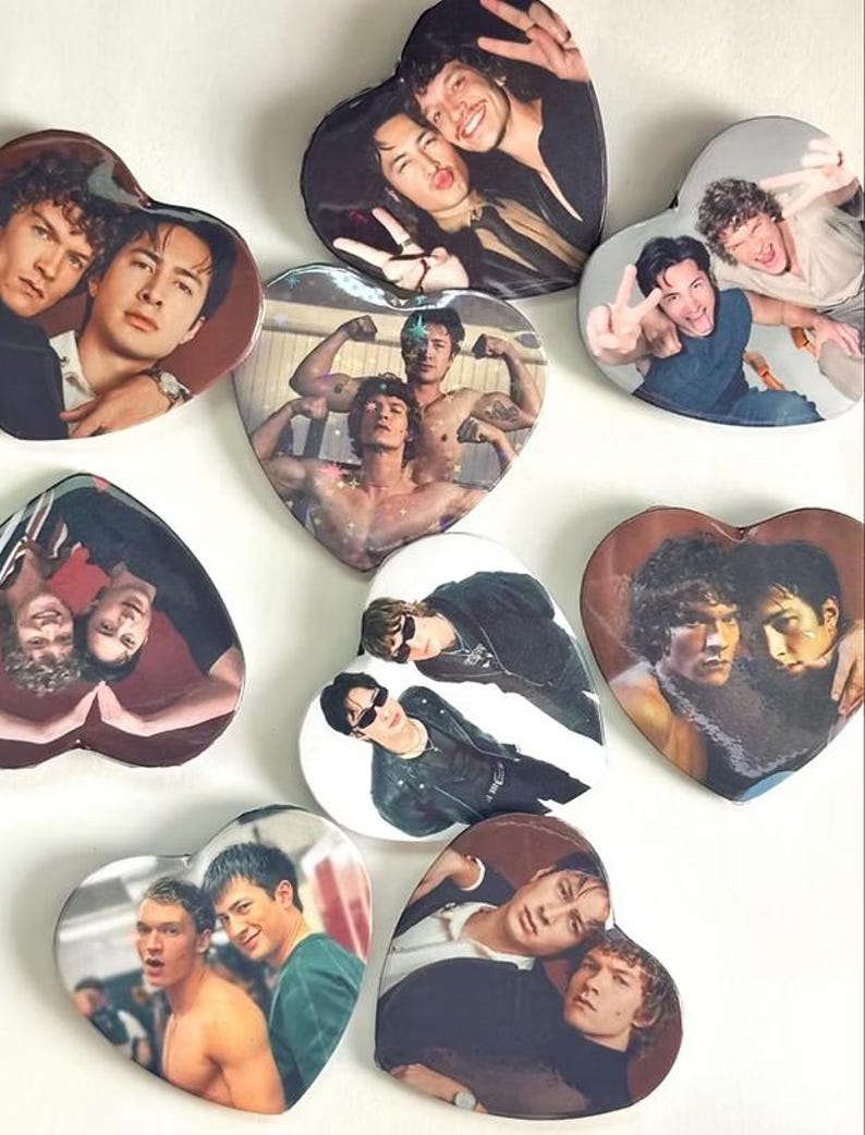 May include: A collection of nine heart-shaped pins featuring various photographic portraits of two individuals. The images display the pair in different poses, outfits, and settings, including casual wear, shirtless shots, and sunglasses, with glossy finishes.
