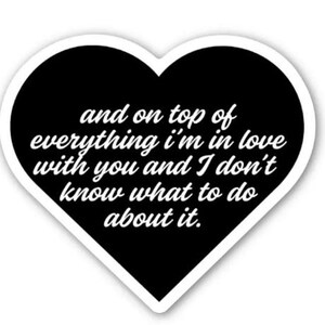 May include: A heart-shaped sticker with a black interior and white border. The sticker features the text "and on top of everything I'm in love with you and I don't know what to do about it" in a white, cursive font.