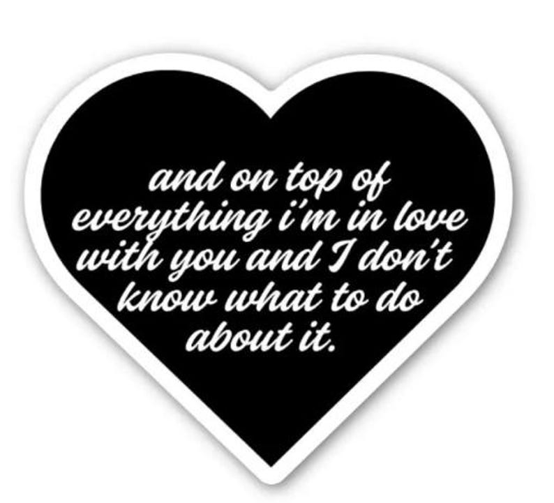 May include: A heart-shaped sticker with a black interior and white border. The sticker features the text "and on top of everything I'm in love with you and I don't know what to do about it" in a white, cursive font.