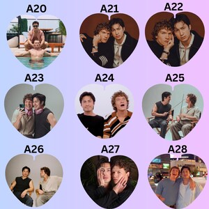 May include: A collection of nine heart-shaped photo stickers labeled A20 through A28, each featuring different portraits of two men in various settings, including poolside, studio shots, and urban environments, with diverse clothing and poses.