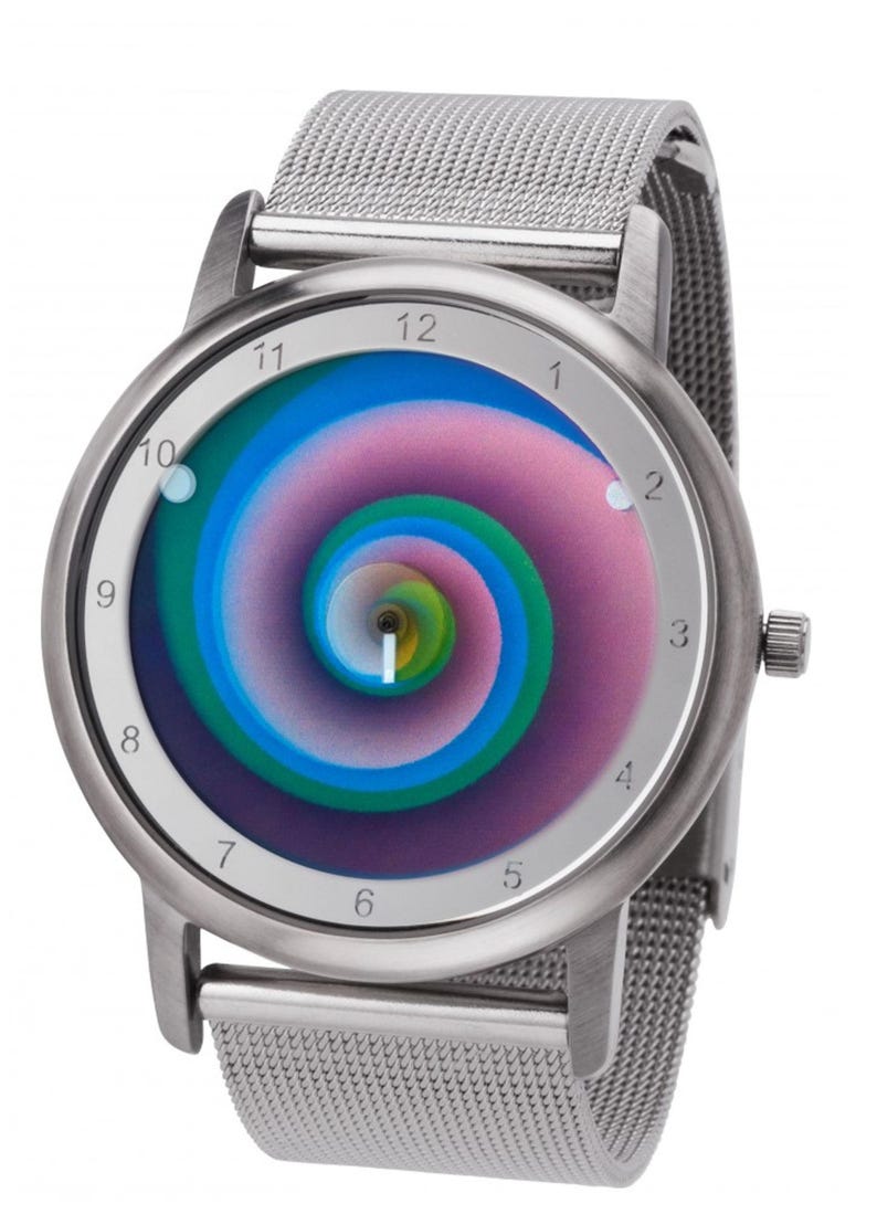 May include: Silver wristwatch with a mesh band and a round face. The watch face features a colorful, swirling spiral design in shades of blue, green, and pink. The watch has a silver bezel and a crown on the side.