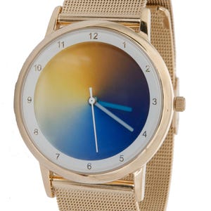 May include: Gold-toned wristwatch with a mesh band. The watch face features a gradient design, transitioning from yellow to blue. The watch has white numerals and blue hands. A stylish accessory.
