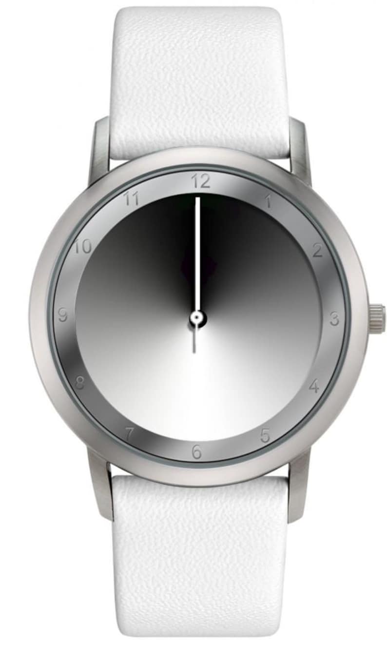 May include: A minimalist wristwatch with a silver-toned case and a gradient gray dial. The watch features a white leather strap. The hands are black and white. The watch face displays the numbers 1 through 12.
