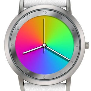 May include: A round wristwatch with a silver-colored case and a white leather strap. The watch face displays a vibrant rainbow gradient, with the hour and minute hands pointing to 12 and 3 o'clock. The watch has a simple, modern design.