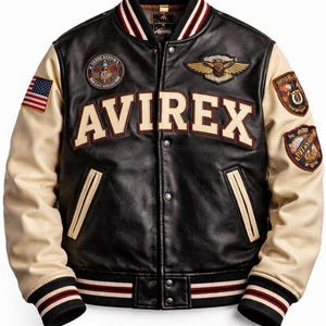 Puede incluir: Una chaqueta universitaria de cuero negro con mangas de color crema, que presenta la palabra AVIREX en letras grandes en el pecho. La chaqueta incluye varios parches bordados, una pequeña bandera estadounidense en la manga derecha y ribetes acanalados.