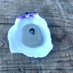 May include: A white resin climbing hold with a purple rim and a gray stone insert with a hole in the center.
