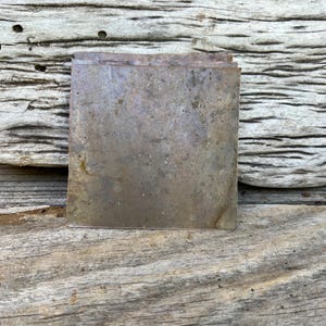 May include: A stack of four square metal sheets with a rustic, weathered, and oxidized finish. The sheets have a mottled brown, gray, and orange color.