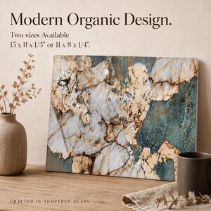 May include: Rectangular tempered glass art piece with a modern organic design. The artwork features a marble-like pattern in shades of white, beige, and teal. The text on the image reads "Modern Organic Design" and "Crafted in Tempered Glass". Available in two sizes: 15 x 11 x 1/3" or 11 x 8 x 1/4".