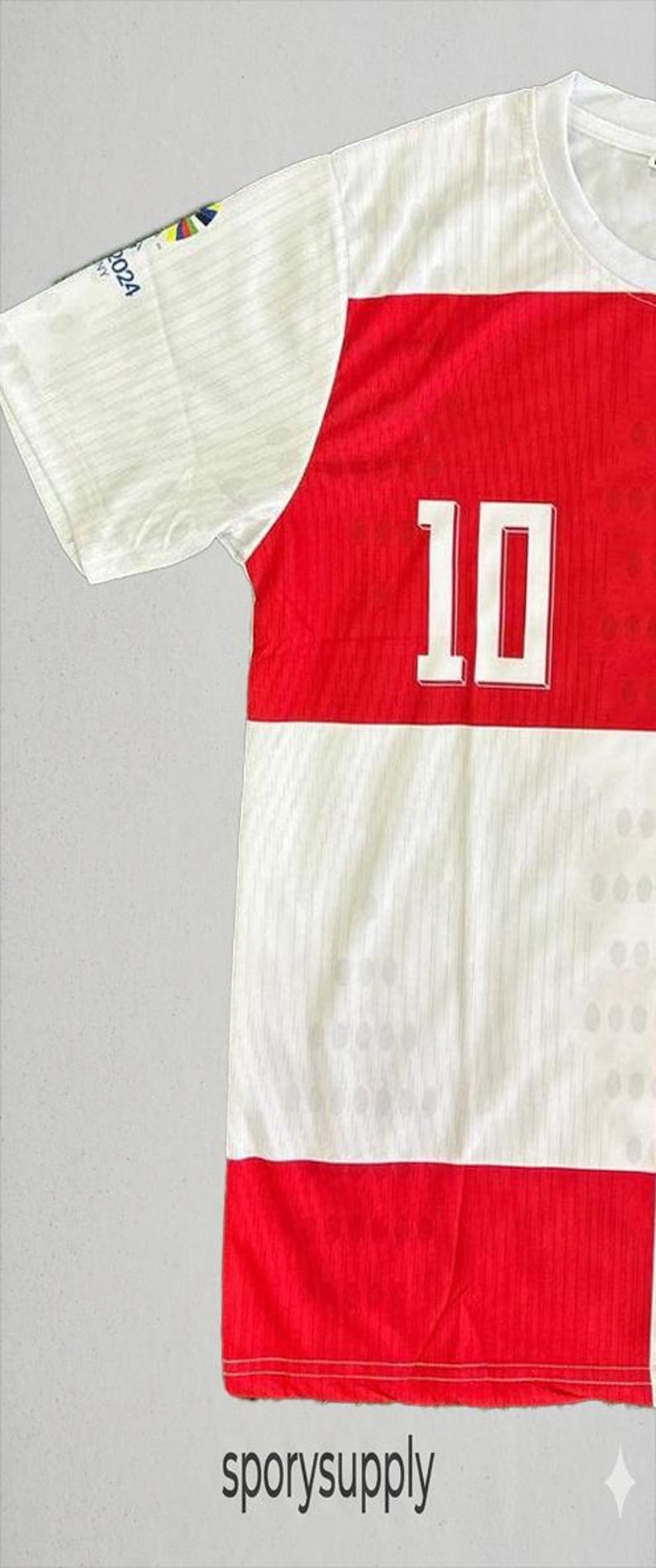 May include: A white and red athletic jersey with the number 10 in white. The jersey has a white upper section and a red lower section. The text "sporysupply" is at the bottom.