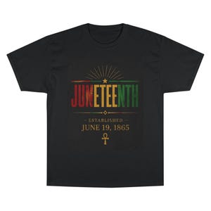 Puede incluir: Camiseta negra con la palabra "Juneteenth" en rojo, amarillo y verde, y el texto "Established June 19, 1865" debajo. El diseño incluye una estrella y un símbolo Ankh.
