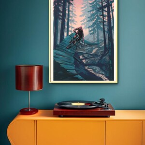 May include: A framed illustration of a mountain biker riding through a forest. The biker is wearing a red and black jersey and a helmet. The forest is filled with tall trees and the sky is a soft pink color.