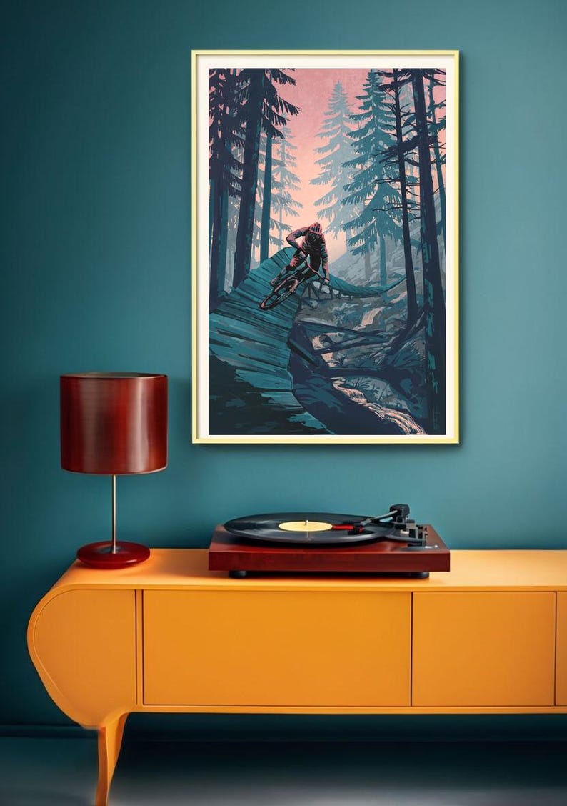May include: A framed illustration of a mountain biker riding through a forest. The biker is wearing a red and black jersey and a helmet. The forest is filled with tall trees and the sky is a soft pink color.