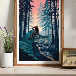 May include: A framed illustration of a mountain biker riding a trail through a forest. The scene is set at dusk with a pink and orange sky. The trees are a deep blue-green color.