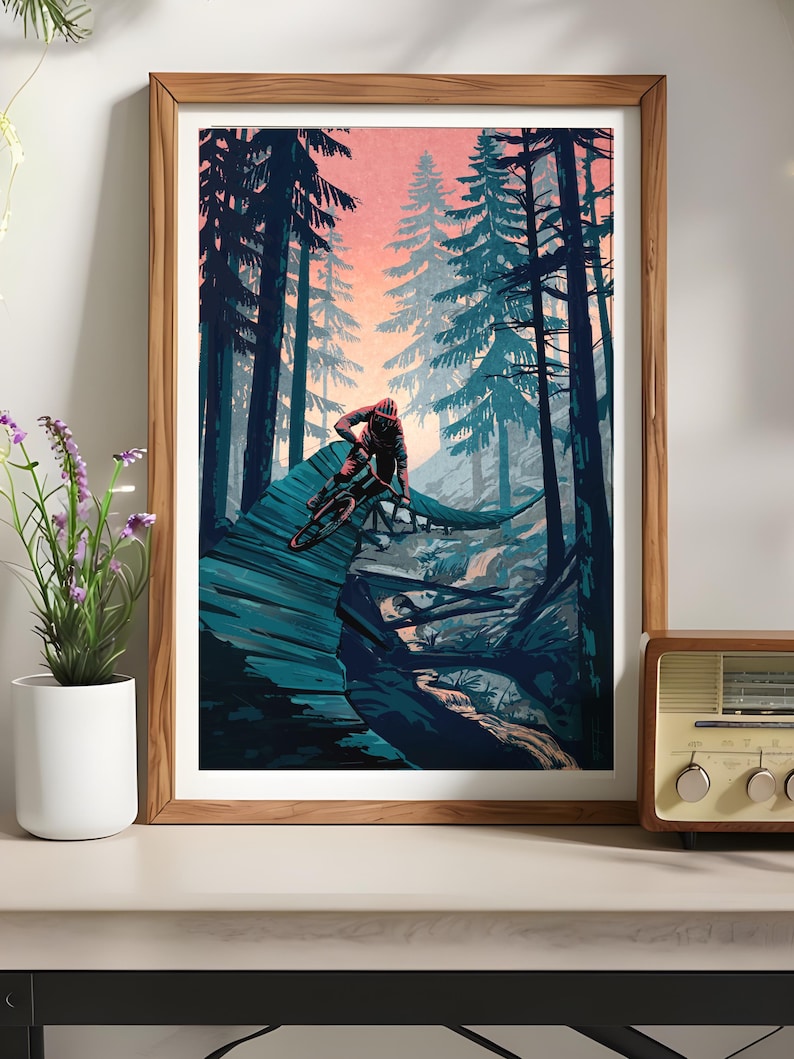 May include: A framed illustration of a mountain biker riding a trail through a forest. The scene is set at dusk with a pink and orange sky. The trees are a deep blue-green color.